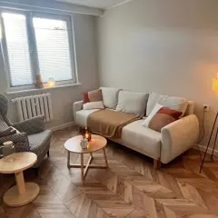 Przytulny gabinet terapeutyczny z sofą, fotelem i lampą.